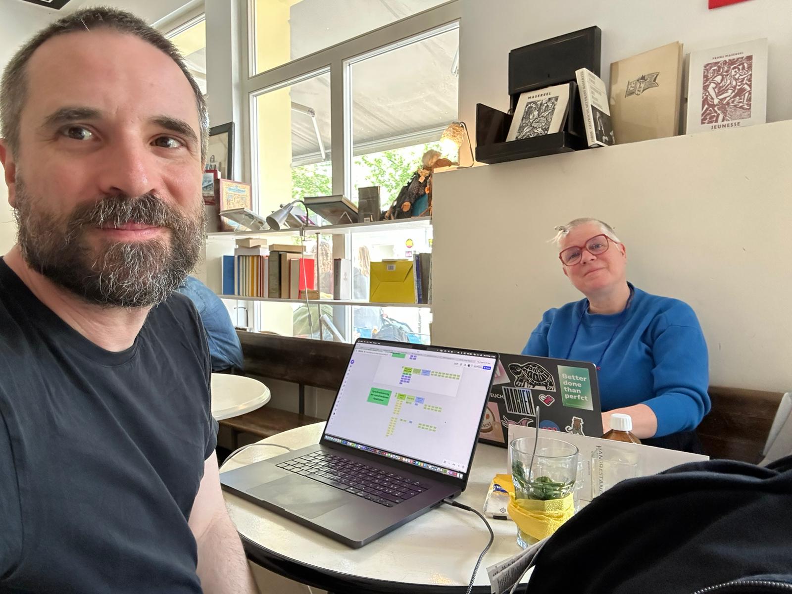 Nadja arbeitet mit einem Kanban-Board am Laptop im Café