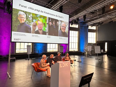 Nadja auf einer Bühne im Gespräch mit einem Panel